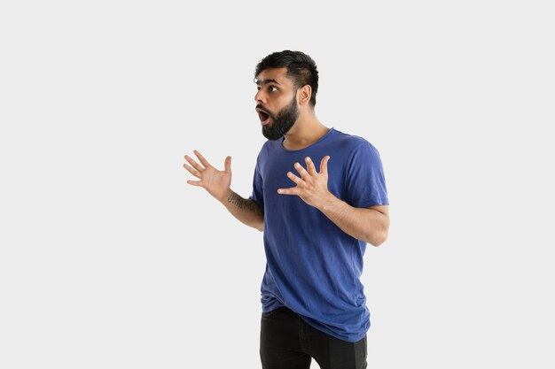 Beautiful male half-length portrait isolated on white wall. Young emotional hindu man in blue shirt. Facial expression, human emotions, ad concept. Astonished, shocked, crazy happy.