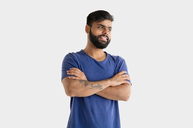 Beautiful male half-length portrait isolated on white wall. Young emotional hindu man. Facial expression, human emotions, ad concept. Smiling, standing confident with crossed hands.