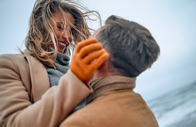 恋愛中​の​美しい​夫婦​は​、​寒い​季節​に​コート​を​着た​海岸​で​お互い​を​楽しんでいます​。
