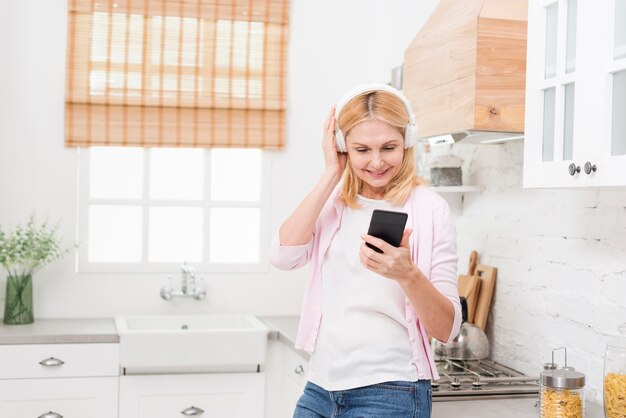 Beautiful mature woman listening to music in the kitchen