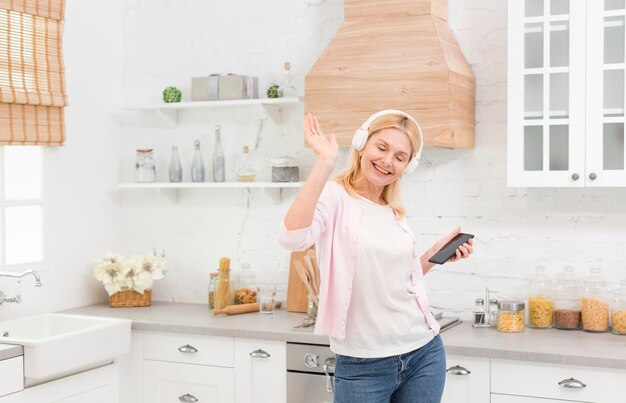 ヘッドフォンで音楽を聴いて楽しんでベッドでスマイリー熟女 無料の写真