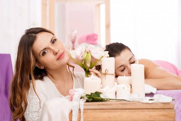 Beautiful messeur sitting behind lighted candles, holding tender flowers