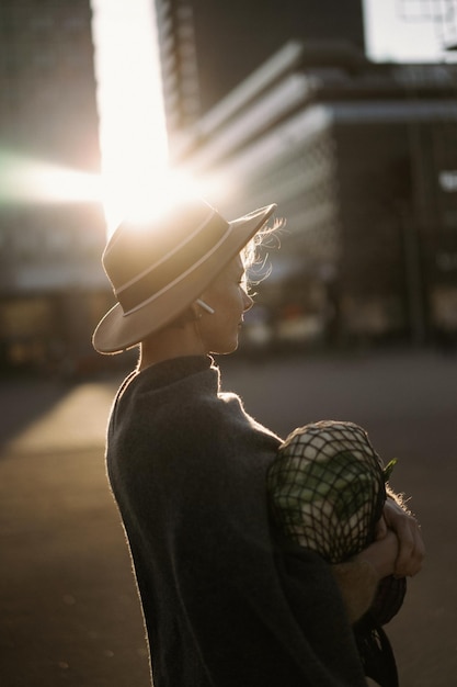 大都会の中心部で短いヘアカットの帽子をかぶった美しい中年女性。クローズアップポートレート、ソフトバックライト。