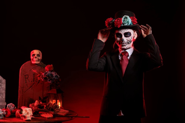 Beautiful model in costume with skull make up celebrating traditional mexican holiday with goddess of death costume. La cavalera catrina culture celebration with body art over black background.