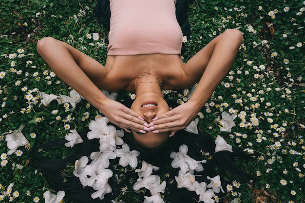 Beautiful model laying in a field with white flowers