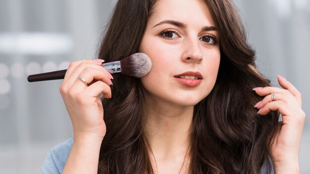 Beautiful model posing with powder brush