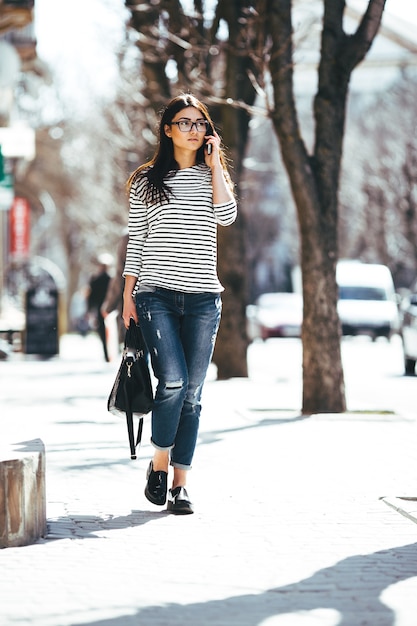 Free photo beautiful model in a striped sweater and is talking on the phone.