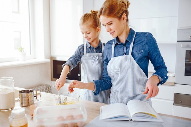 beautiful mother in a blue shirt and apron is preparing dinner at home in the kitchen