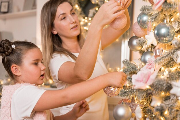 Beautiful mother and daughter decorating the christmas tree