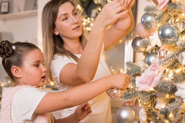 Красивая мать и дочь украшают елку