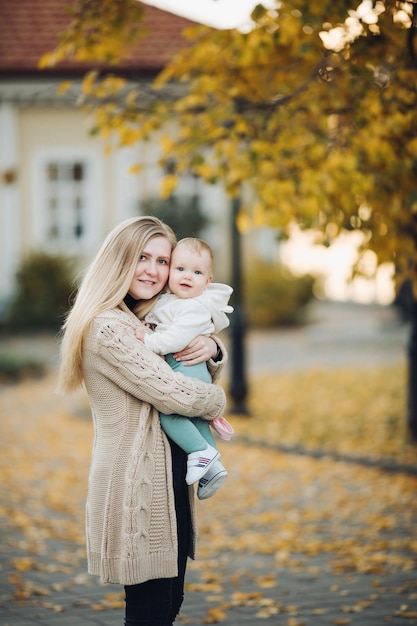 Beautiful mother and daughter walking in the park in autumn portrait Mom and daughter family concept A little girl in her mother's arms