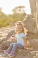 Free photo beautiful mother and her cute long haired daughter are walking on meadow of stone