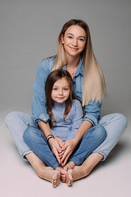 Beautiful mother sits with her pretty daughter and smile