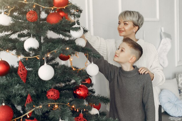 Beautiful mother in a white sweater. Family in a christmas decorations. Little boy in a room