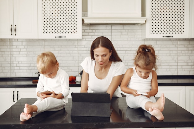 Beautiful mother with cute children at home in a kitchen