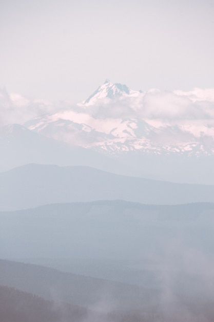 Beautiful mountain covered in snow and surrounded with clouds during a foggy weather