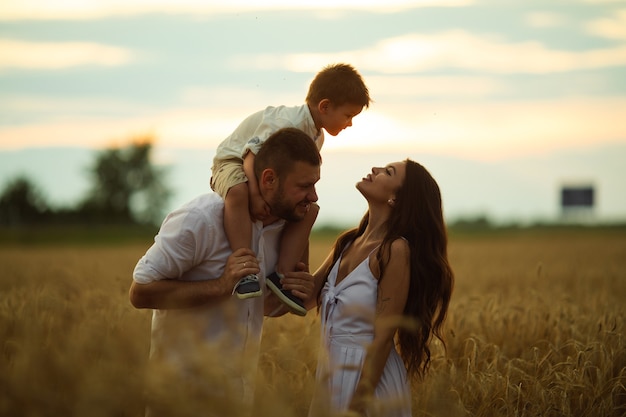 Beautiful mum, dad and their cute little child have fun together and smiles outside