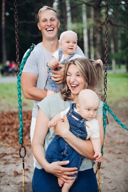 Beautiful mum, dad and two caucasian children have fun together and smiles outside