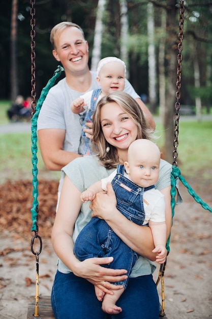 Beautiful mum, dad and two caucasian children have fun together and smiles outside