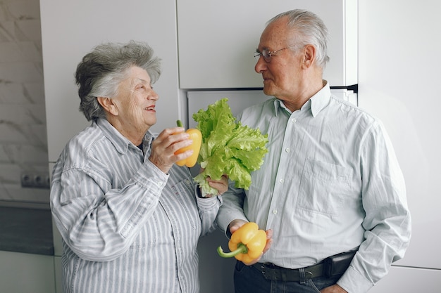 Beautiful old couple prepare food in a kitchen