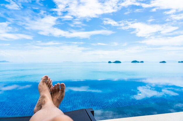 Beautiful outdoor swimming pool with sea ocean on white cloud blue sky