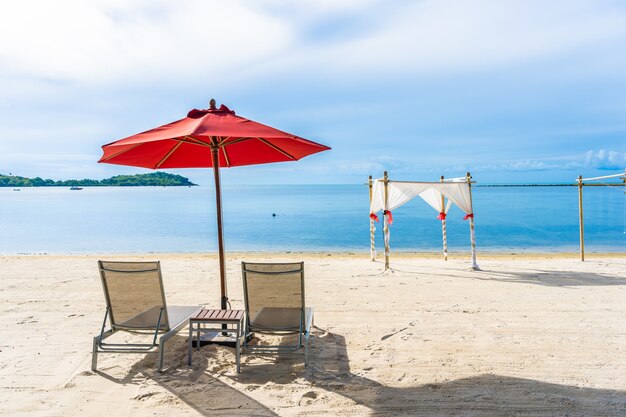 Beautiful outdoor tropical beach sea ocean with umbrella chair and lounge deck around there on white cloud blue sky