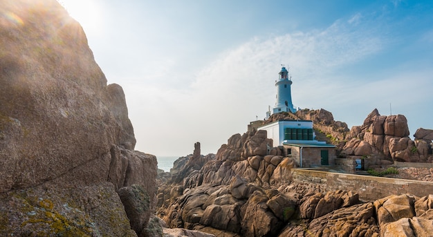 Beautiful panoramic shot of cliffs with a lighthouse and a calm sea