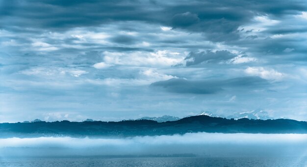 曇り空の下で背景に丘のある海の美しいパノラマ写真