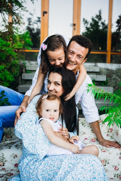 Beautiful parents and their little girls sit on footsteps outside 