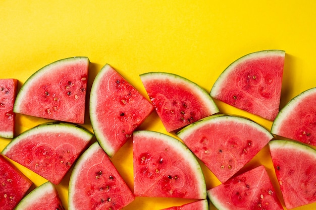 Free photo beautiful pattern with fresh watermelon slices on yellow bright background. top view. copy space.