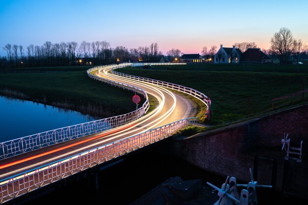 Красивая фотография улицы с автомобильными световыми дорожками у реки ночью