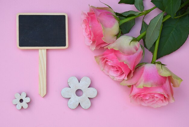 Beautiful pink roses with wooden shaped little flowers isolated on a pink background