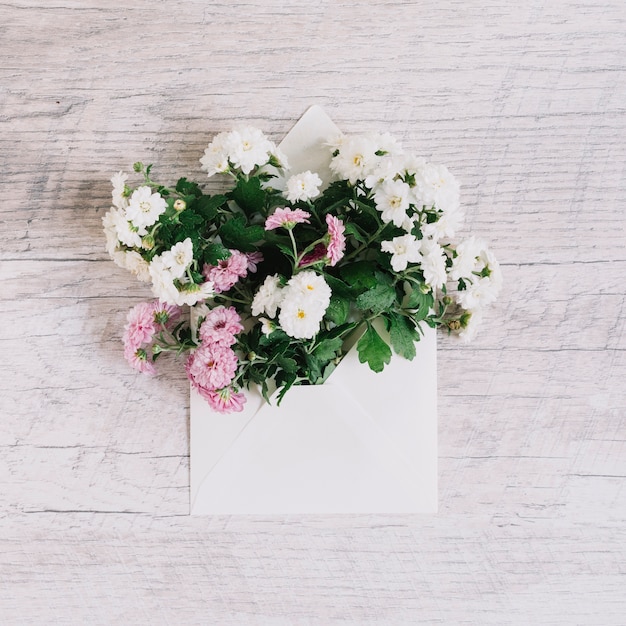 나무 질감 배경에 봉투에 아름 다운 분홍색과 흰색과 꽃 꽃