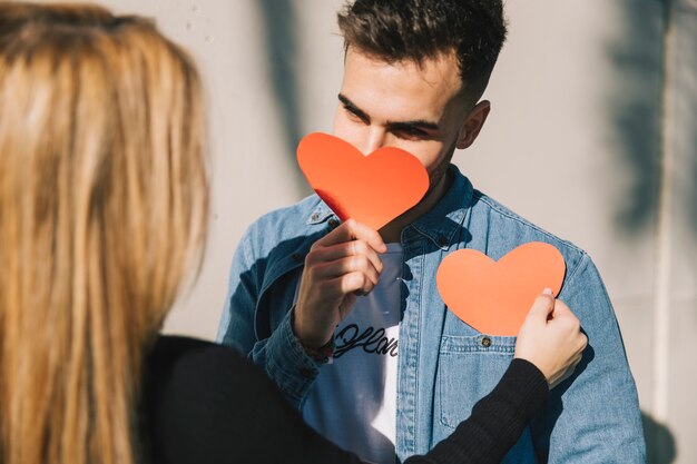 Beautiful playful couple with paper hearts