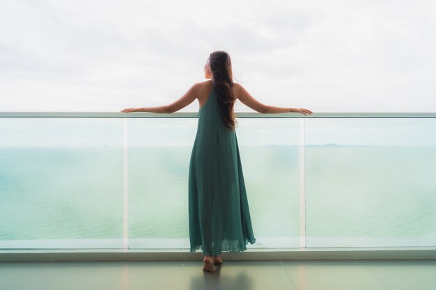 Beautiful portrait young asian woman happy smile relax at balcony with sea ocean