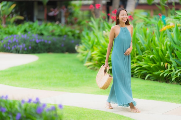 Улыбка красивой азиатской женщины портрета счастливая ослабляет с прогулкой в саде