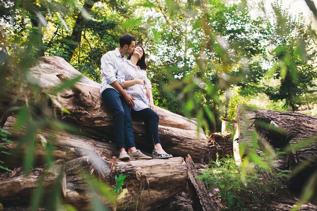 Красивая беременная пара расслабляющий снаружи в лесу