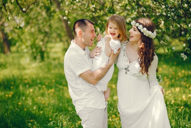 그녀의 남자 친구와 그들의 작은 딸과 함께 긴 하얀 드레스를 입고 아름다운 임신 한 여자