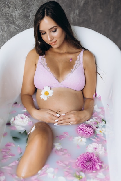 분홍색 란제리의 아름다운 임신 한 여자는 목욕에있다