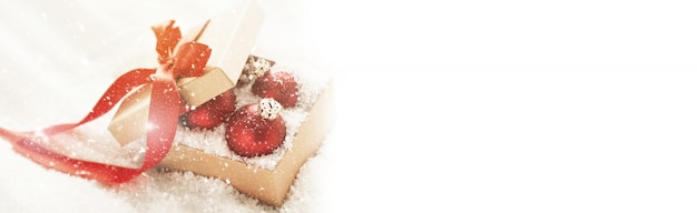Красивые красные классические блесна или рождественские украшения в подарочной коробке со снегом, концепция Рождества