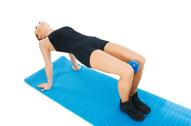 Beautiful red girl exercising with ball and yoga mat