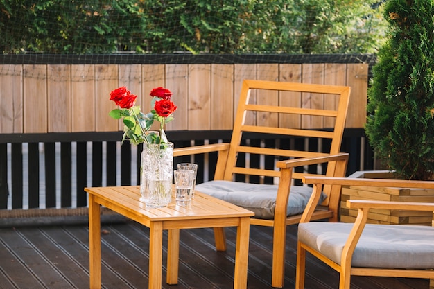 옥상에서 나무 테이블에 아름 다운 빨간 장미 꽃병 및 음료