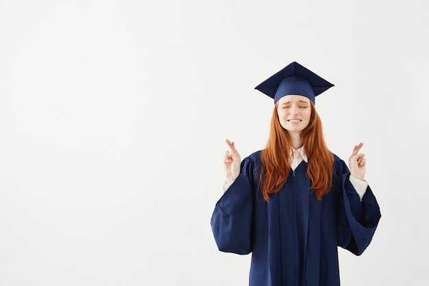 Beautiful redhead female graduate praying. 