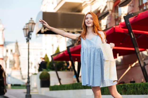 Beautiful redhead girl in dress holding a city guide map