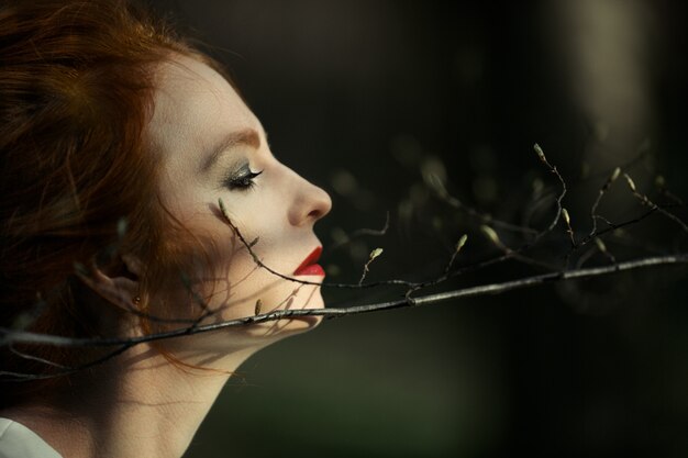 Beautiful redhead girl enjoys nature in the woods