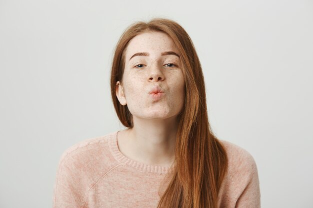 Beautiful redhead girl fold lips, blowing kiss