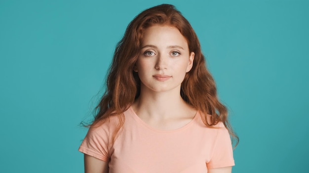 Beautiful redhead girl intently looking in camera over colorful background