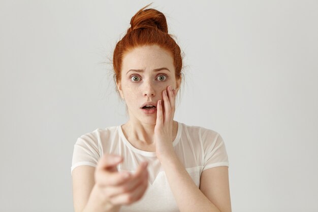 Beautiful redhead girl with hair knot having scared and frightened look