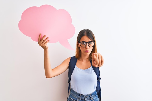 Free photo beautiful redhead student woman wearing a backpack and holding speech bubble pointing with finger to the camera and to you hand sign positive and confident gesture from the front