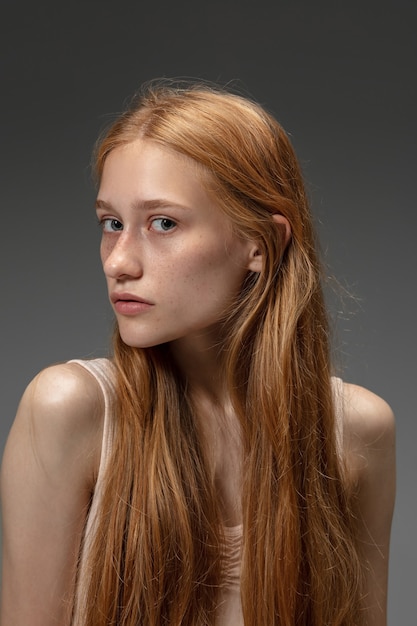 Beautiful redhead woman on grey studio background, fashion